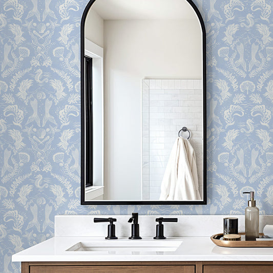 A stunning Dreamy Mermaid wallpaper in a soft coastal blue color palette with seahorses, kelp, coral and shells, in a modern bathroom.