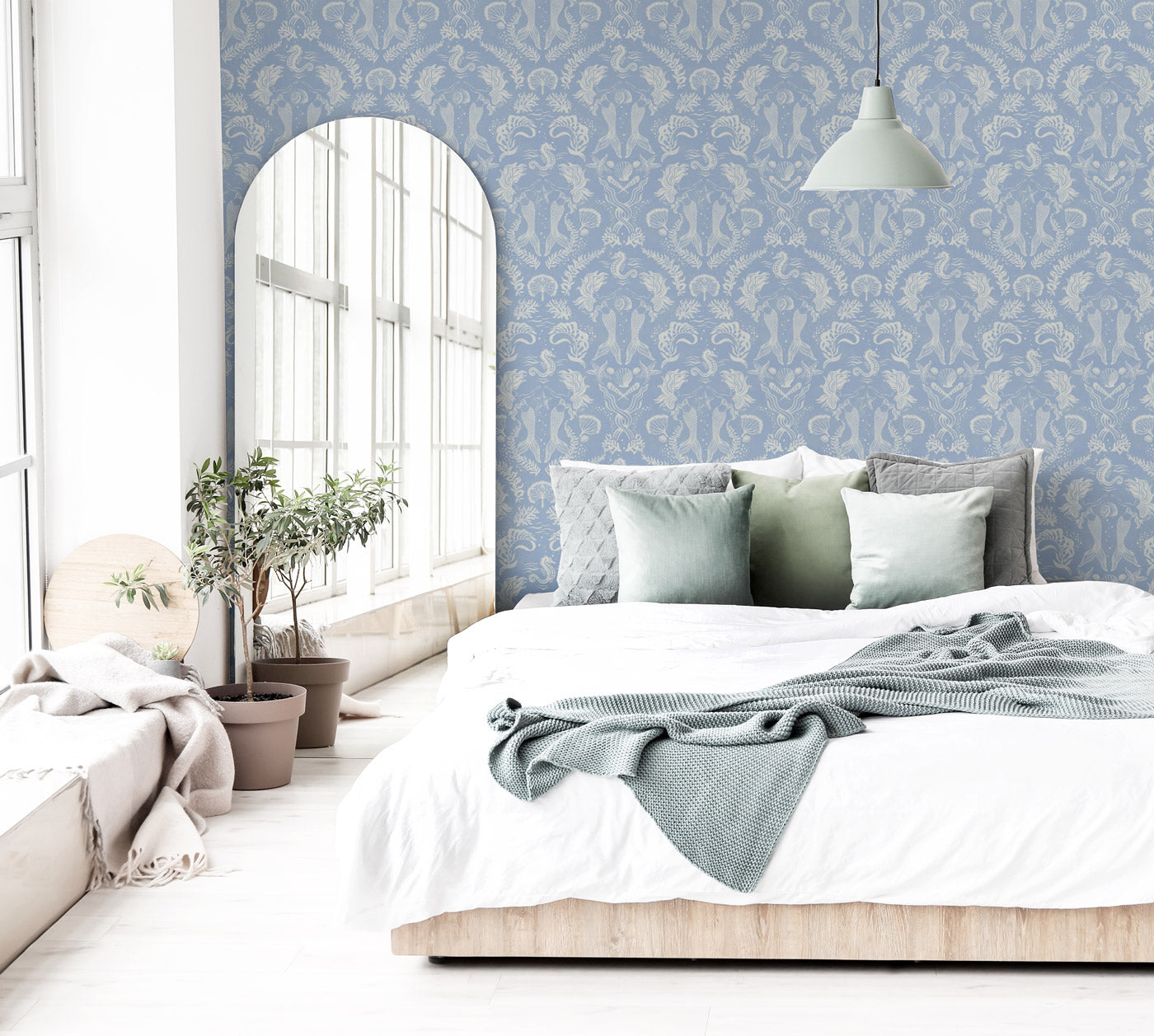 A stunning Dreamy Mermaid wallpaper in a soft coastal blue color palette on a statement wall in a brightly lit bedroom.