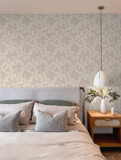 A graphic brushstroke floral wallpaper set against a soft pink background adds subtle boldness with a feminine edge to a modern bedroom.